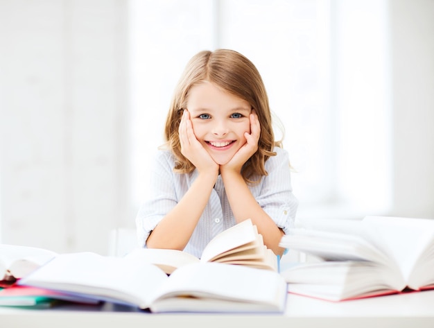 Educazione e concetto di scuola - piccola studentessa che studia e legge un libro a scuola