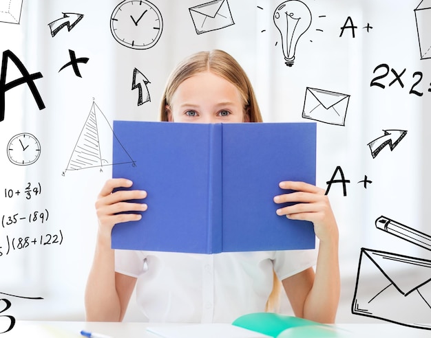 education and school concept - little student girl studying and reading book at school