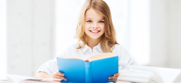 концепция образования и школы - маленькая студентка изучает и читает книгу в школе