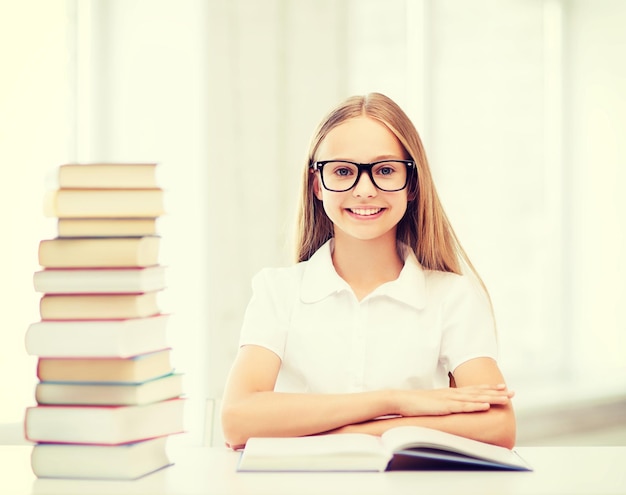 education and school concept - little student girl studying and reading books at school