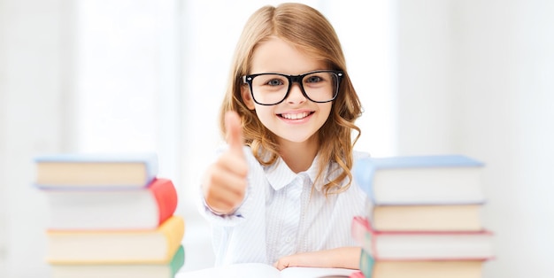 education and school concept - little student girl studying and reading books at school