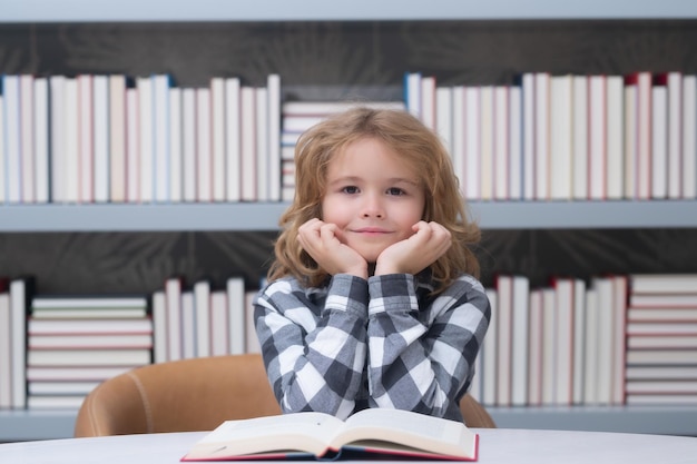 Education and school concept School child studying in school library Portrait of child reading in library on background with books