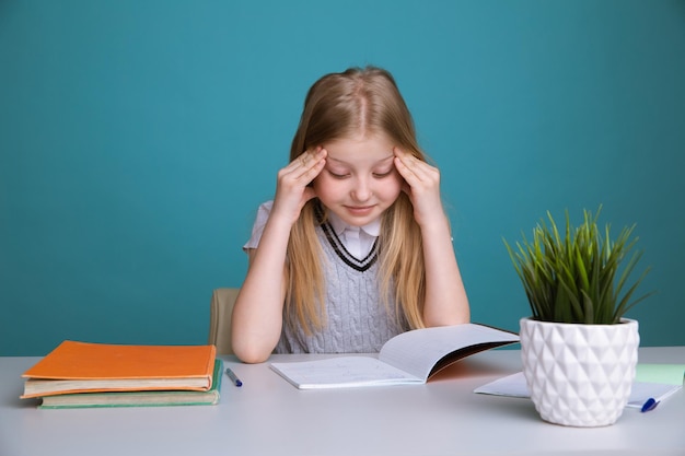 学校でたくさんの本を持っている小さな学生の女の子を笑顔の教育と学校の概念