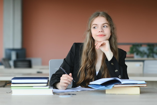 Foto educazione e concetto scolastico studentessa che studia e legge libri a scuola