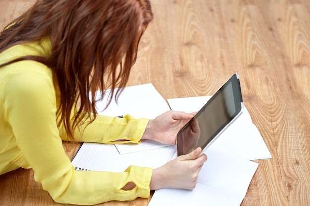 education, school, people, technology and internet concept - close up of female with tablet pc computer and notebooks lying on floor