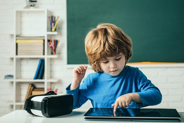 学校の教室でデジタル タブレットと才能のある生徒の男子生徒のための教育学校