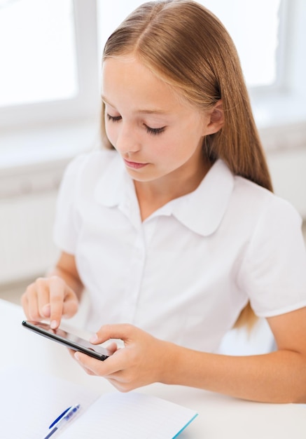 교육, 학교, 기술 및 인터넷 개념 - 학교에서 노트북과 스마트폰을 가진 어린 학생 소녀