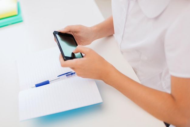 education, school, technology and internet concept - little student girl with notebooks and smartphone at school