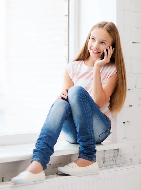 education, school, technology and internet concept - little student girl with smartphone at school