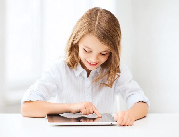 education, school, technology and internet concept - little student girl with tablet pc at school