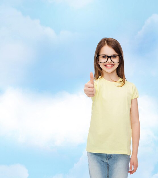 education, school and vision concept - smiling cute little girl in black eyeglasses showing thumbs up