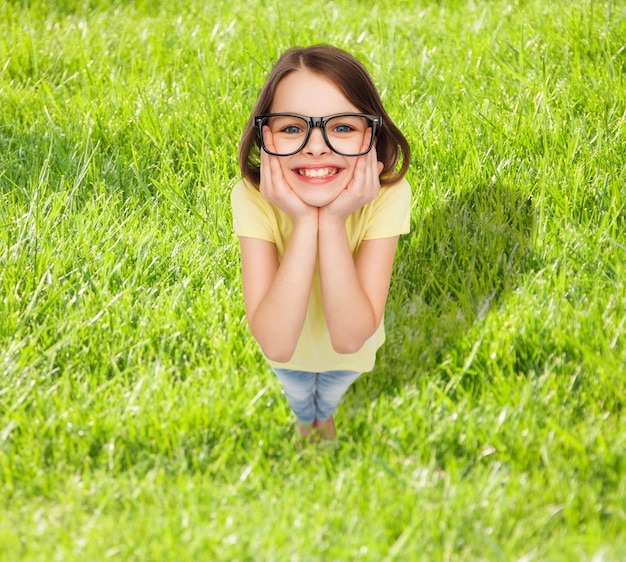 education, school and vision concept - smiling cute little girl in black eyeglasses