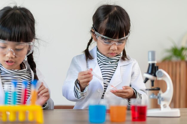 education science chemistry and children concept kids or students with test tube making experiment at school laboratory