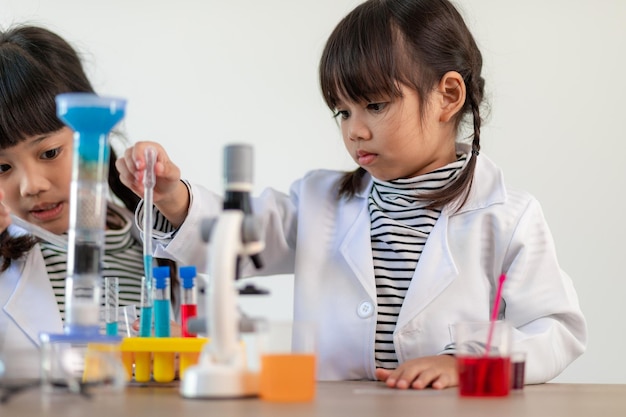 education science chemistry and children concept kids or students with test tube making experiment at school laboratory