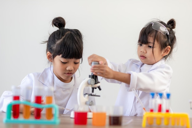education science chemistry and children concept kids or students with test tube making experiment at school laboratory