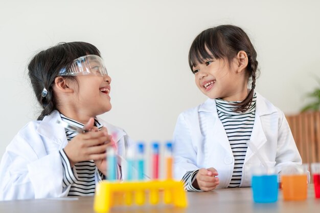 education science chemistry and children concept kids or students with test tube making experiment at school laboratory