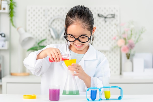 education science and children concept girl in goggles with magnifier studying test tube with chemi