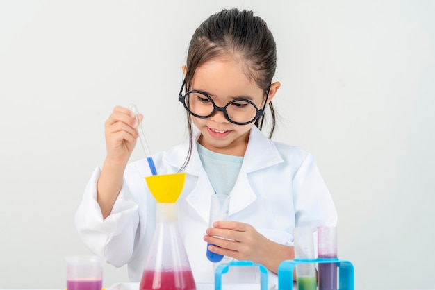 education science and children concept girl in goggles with magnifier studying test tube with chemi