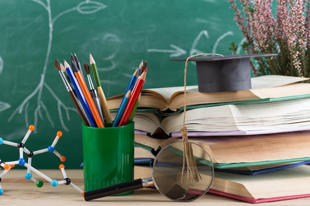 Education and sciences concept books molecule model and graduation cap on the desk in the auditorium photosynthesis formulas on the background