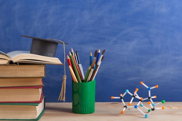 Education and sciences concept books on the teacher desk in the auditorium chalkboard on the background