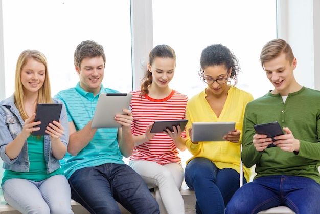 Foto concetto di istruzione e tecnologia - studenti sorridenti con computer tablet pc a scuola