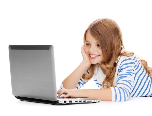 education, technology and internet concept - smiling little student girl with laptop computer lying on the floor