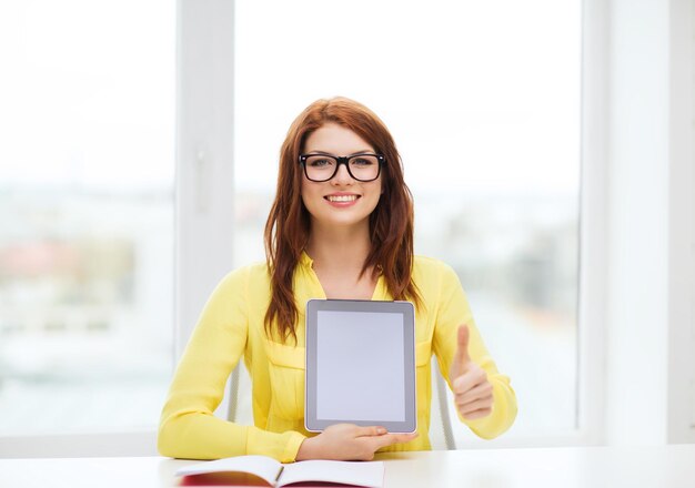 education, technology and internet concept - smiling student girl in eyeglasses with tablet pc at school showing thumbs up