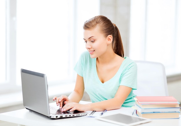 education, technology and internet concept - smiling student girl with laptop