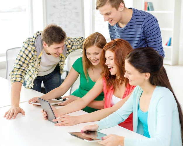 Concetto di educazione, tecnologia e internet - studenti sorridenti con computer tablet pc a scuola