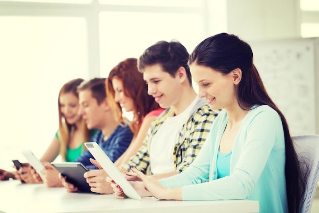 education, technology and internet concept - smiling students with tablet pc computers at school