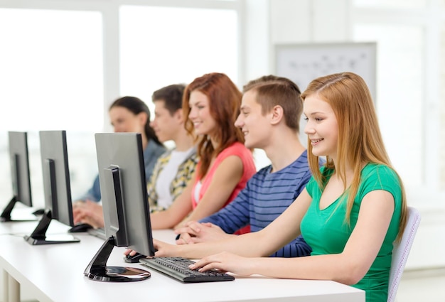 教育、技術、学校のコンセプト-学校のコンピュータークラスでクラスメートと笑顔の女子学生