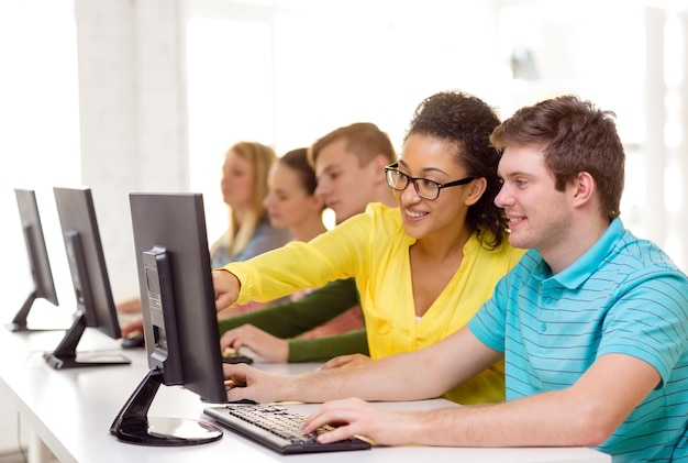 education, technology and school concept - smiling students in computer class at school