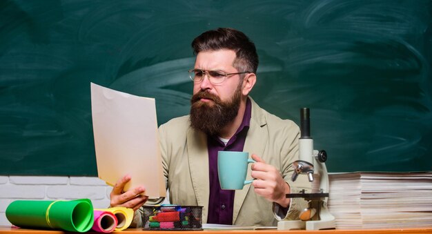 Educational concept back to school using microscope biology education serious bearded man hipster drink tea at school chemistry lesson mature teacher concentrated on work Towards knowledge