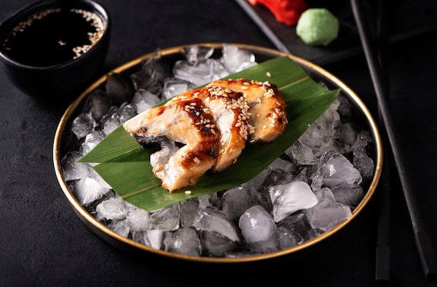 Eel sashimi on ice in a black plate