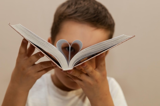 Een 10-jarige jongen heeft de bladzijden van een boek omgeslagen en kijkt er doorheen alsof hij door een verrekijker kijkt