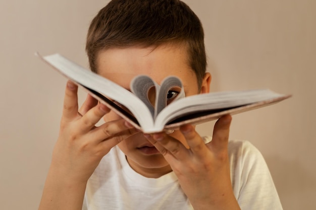 Een 10-jarige jongen heeft de bladzijden van een boek omgeslagen en kijkt er doorheen alsof hij door een verrekijker kijkt