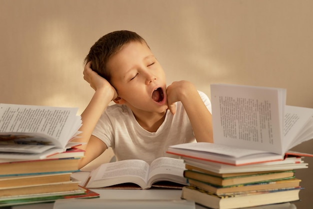 Een 10-jarige jongen leest en studeert aandachtig aan een tafel met stapels boeken