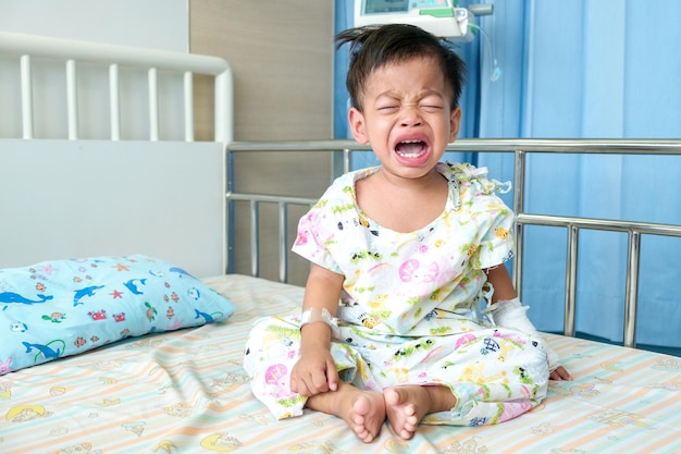 Een 15-jarige Aziatische jongen is ziek en wordt behandeld in het ziekenhuis huilend met een verdrietig gezicht