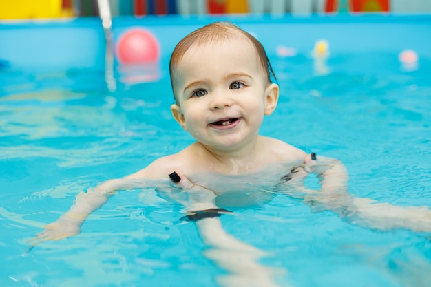 Een 2-jarig jongetje leert zwemmen in een zwembad met een coach Zwemlessen voor kinderen