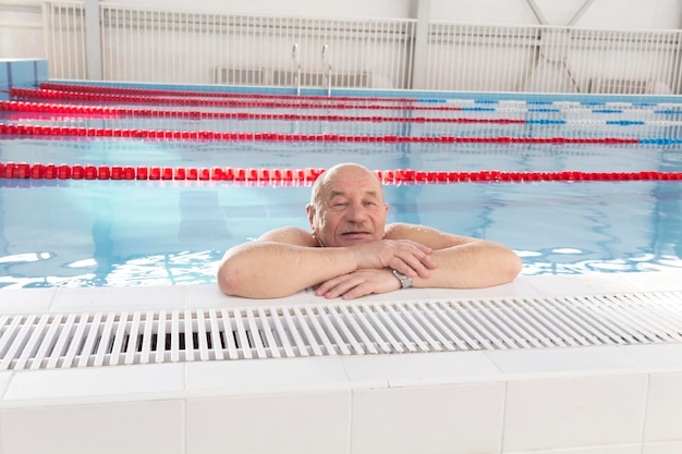 Een 70-jarige gepensioneerde rust aan het zwemmen en herstelt zich in het zwembad met helder en blauw water in het hotel