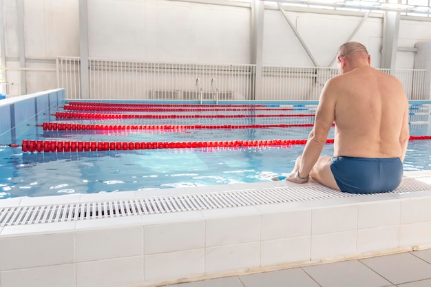 Een 70-jarige gepensioneerde rust aan het zwemmen en herstelt zich in het zwembad met helder en blauw water in het hotel
