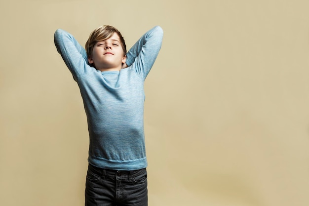 Een 9-jarige jongen rekt zich vermoeid uit een knappe jongen in een blauwe trui en grijze spijkerbroek moeilijkheden bij het leren en stress gele achtergrond ruimte voor tekst