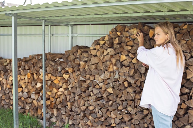 Een aantrekkelijk meisje in een landhuis bereidt brandhout voor Brandhout voorbereiden op het koude seizoen