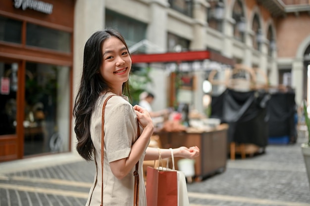 Een aantrekkelijke Aziatische vrouw geniet van haar winkeldag op de stadsmarkt in het weekend