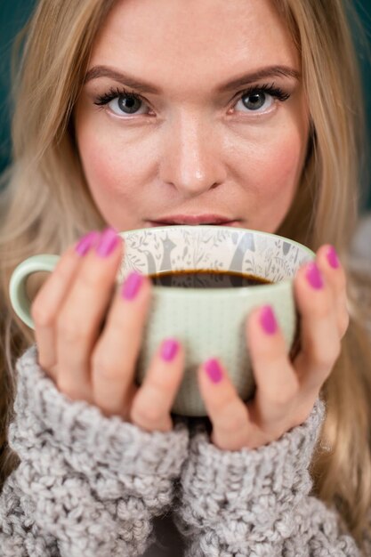 Foto een aantrekkelijke blonde vrouw bedekt haar gezicht met een grote kop koffie