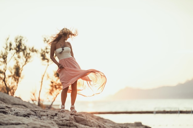 Een aantrekkelijke jonge vrouw danst en heeft plezier terwijl ze geniet van een zomervakantie aan de prachtige kust.