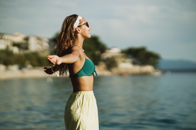 Een aantrekkelijke jonge vrouw in bikini heeft plezier op het strand en geniet van een zomervakantie.