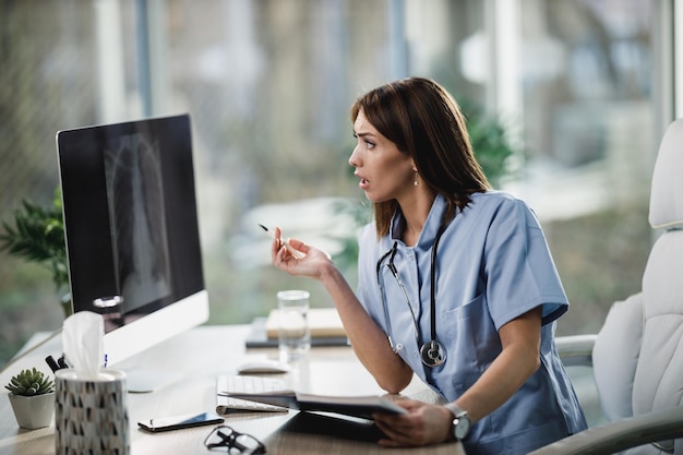Een aantrekkelijke jonge vrouwelijke verpleegster die röntgenfoto's analyseert op de computer in het ziekenhuis.