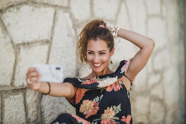 Een aantrekkelijke lachende vrouw die selfie of video-oproep maakt met haar smartphone terwijl ze geniet van een zomerdag.