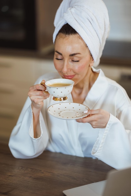 Een aantrekkelijke vrouw in badjas die geniet van lekkere koffie en thuis een ochtendritueel heeft.